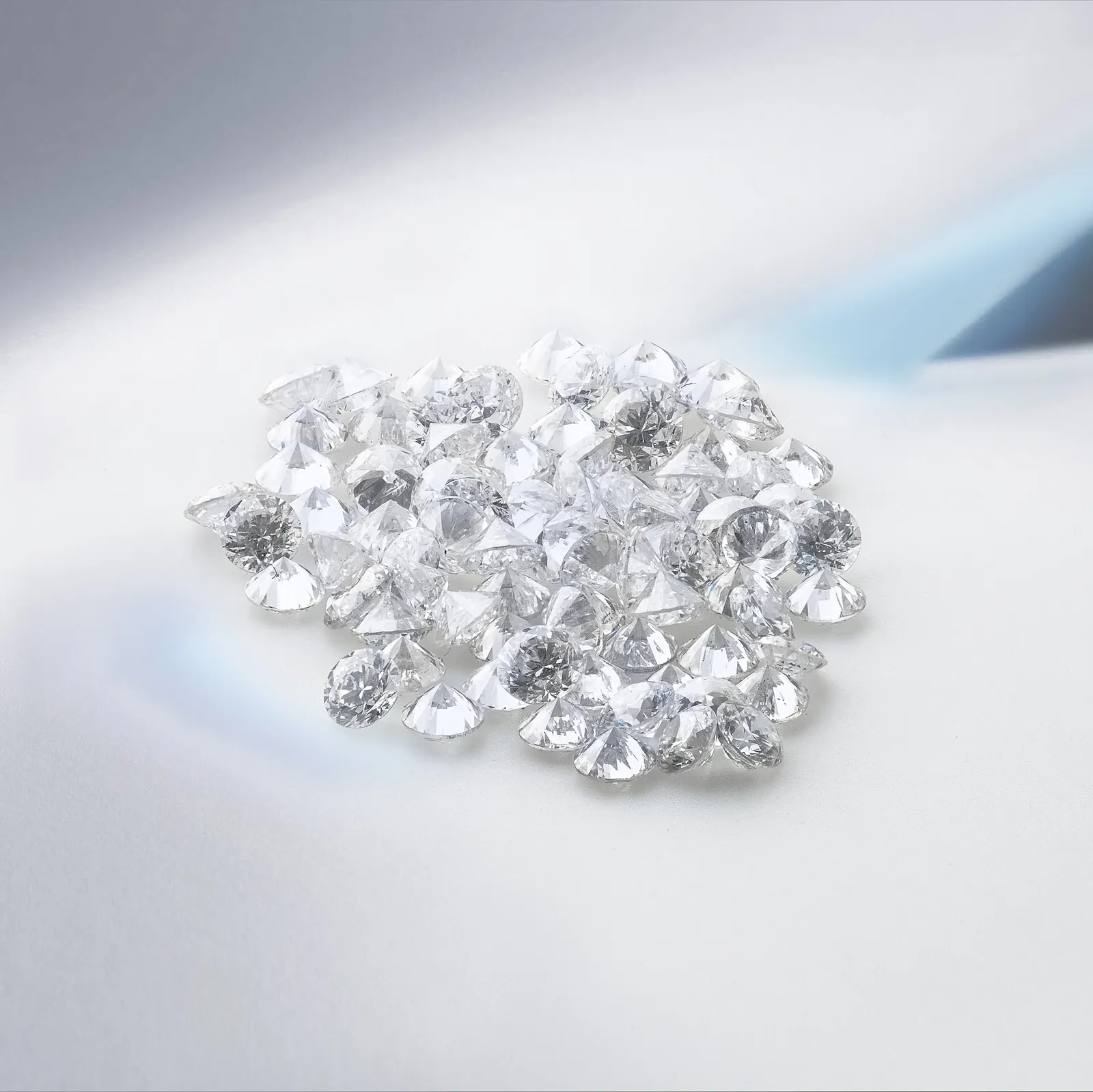 Decenas de diamantes redondos incoloros cultivados en laboratorio sobre una superficie blanca